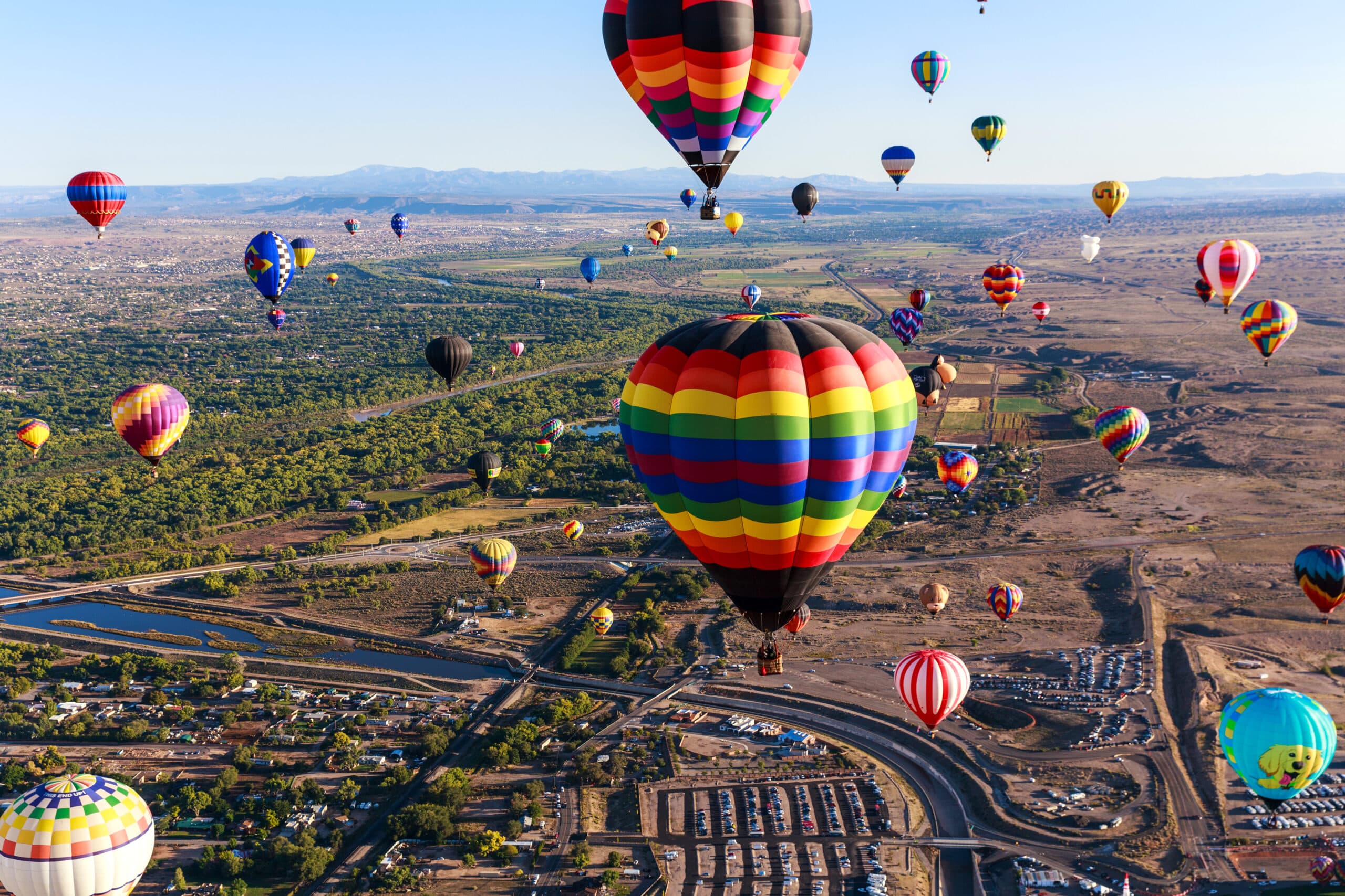Dozens of colorful hot-air balloons drifting over the desert plain and river valley at the Albuquerque International Balloon Fiesta.